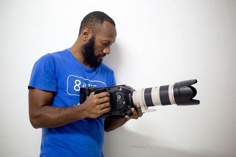 Iuma Bani holding a cinema camera with a telephoto lens